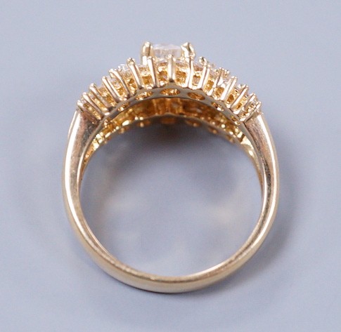 A modern 18ct gold and graduated round and baguette cut diamond set three row cluster ring, size M, gross weight 7.4 grams